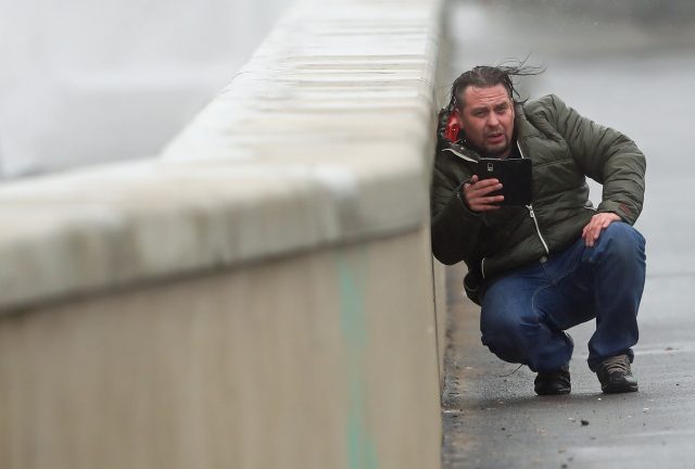 A man shelters from the waves and high wind at Lahinch in County Clare on the West Coast of Ireland