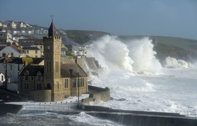 Waves break around the church in the harbour at Porthleven, Cornwall