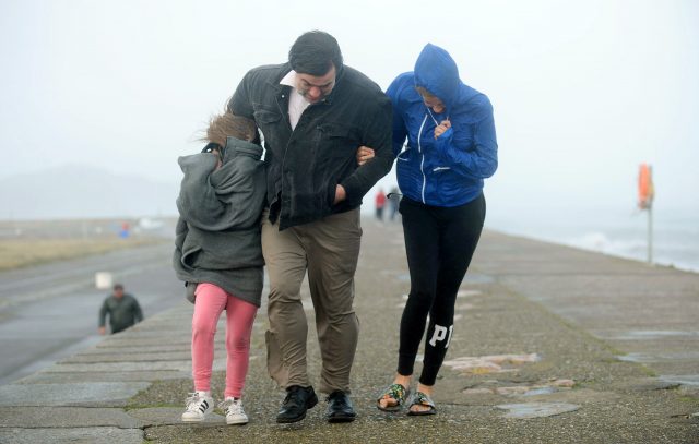 A family walking on pier wall during storm Ophelia on East Pier in Howth, Dublin
