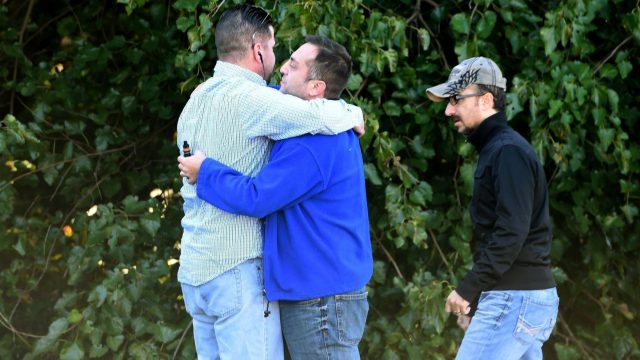Bystanders embrace as police and Emergency Medical Services respond to a shooting at a business park in the Edgewood area