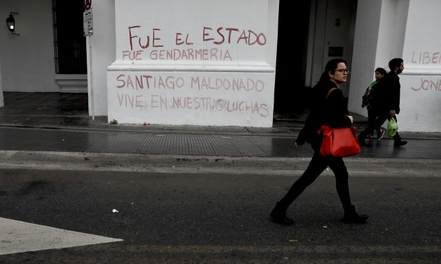 A woman passes graffiti that reads in Spanish: 