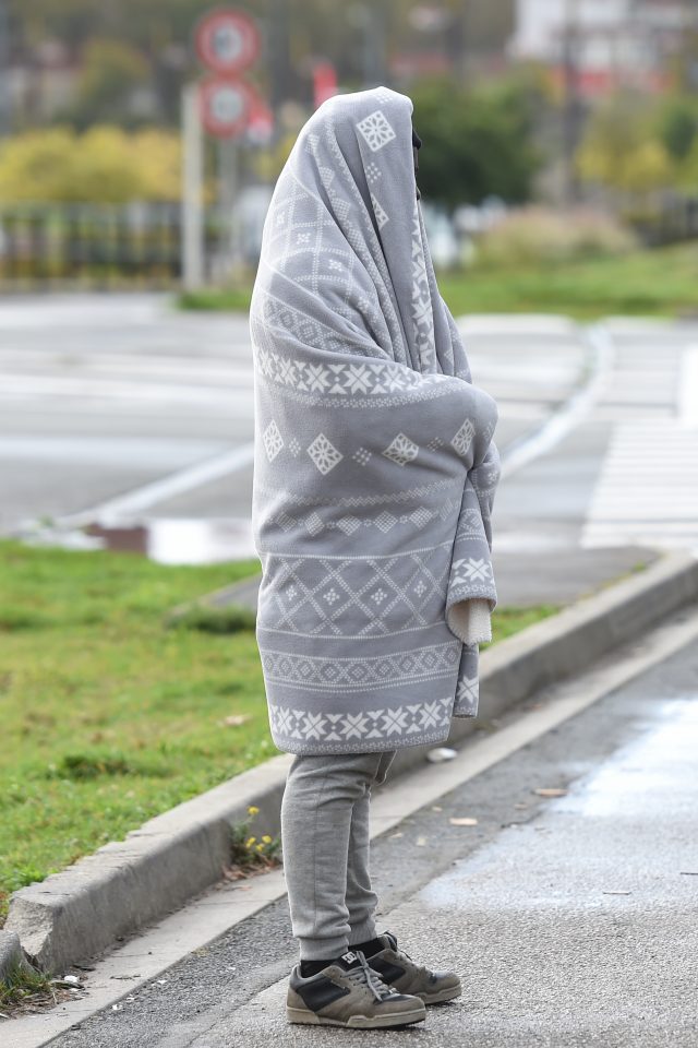 A migrant from Ethiopia uses a donated blanket to keep warm on the streets of Calais
