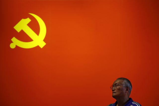 A man stands before a Communist flag
