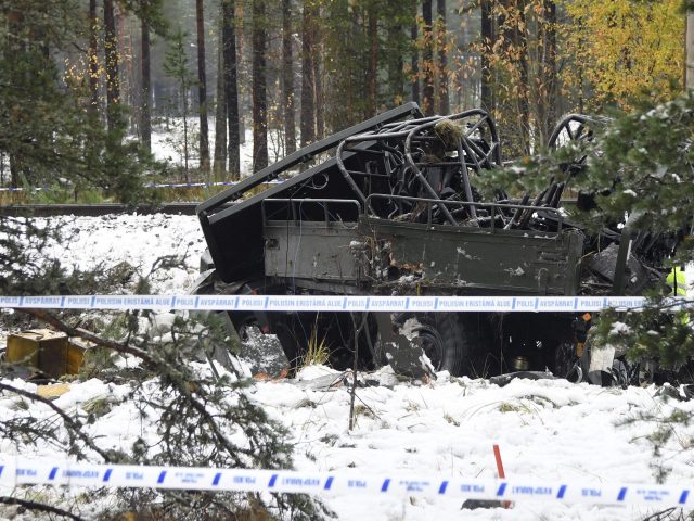 The wreckage of a military truck lays by the side of the  tracks