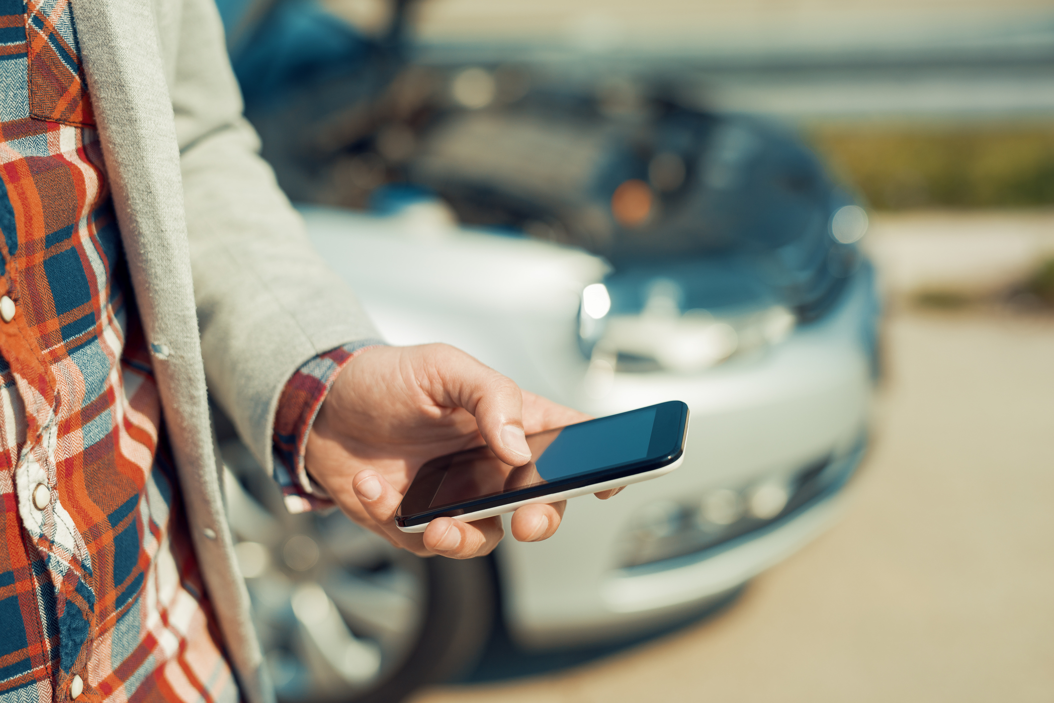 Smartphone users by a car ((Ivanko_Brnjakovic/Getty Images)