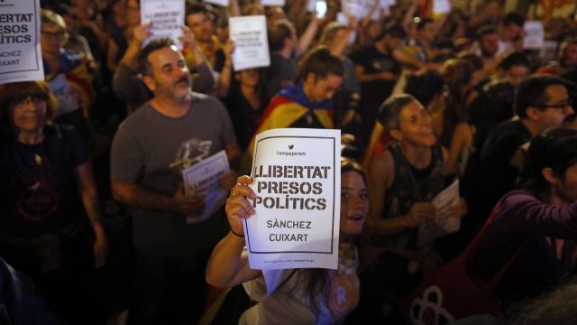 Pro-independence supporters holds signs reading in Spanish