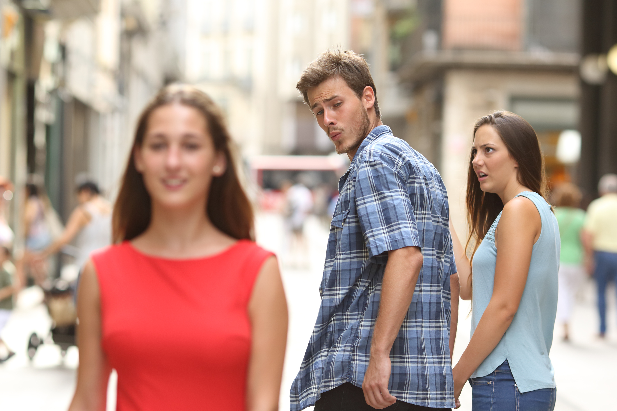 A stock image of a man with his girlfriend looking at another woman