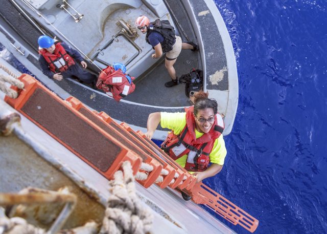 Tasha Fuiava climbs up a ladder to board the amphibious dock landing ship USS Ashland