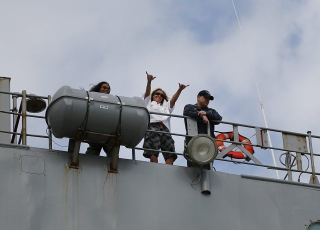 Jennifer Appel raises her arms from the bridge way of the USS Ashland
