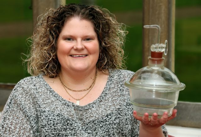 Louise Brown holds the incubator jar in which her embryo was incubated, at the Bourne Clinic in Cambridgeshire (PA)
