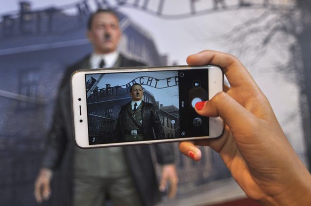 A visitor uses her mobile phone to take a photo of the wax figure of Adolf Hitler