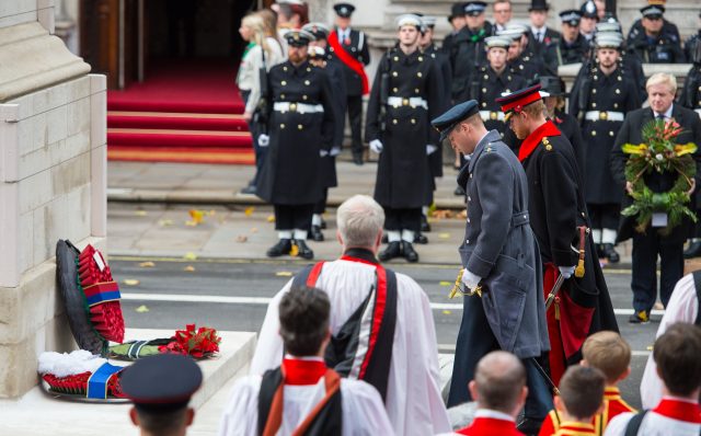 The Duke of Cambridge,  left, and Prince Harry, watched by Foreign Secretary Boris Johnson, bow their heads in respect after laying wreaths