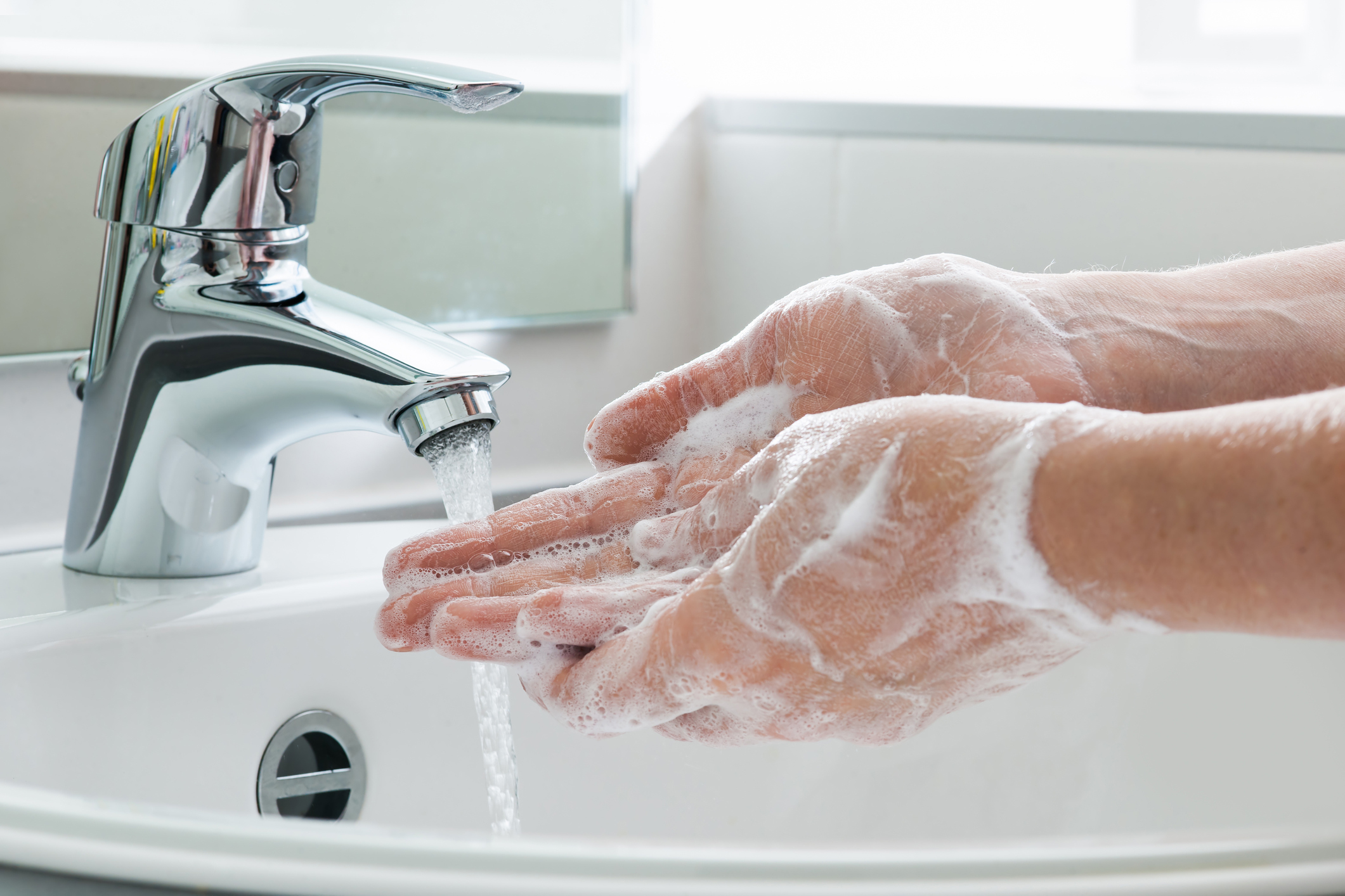 A woman washing her hands in a sink.