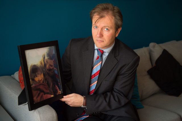 Richard Ratcliffe holding a portrait of his wife and daughter (Dominic Lipinski/PA)