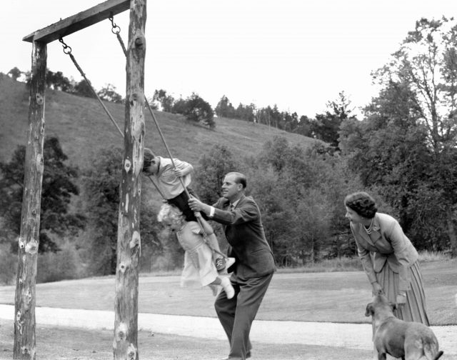 Prince Charles and Princess Anne being pushed on a swing by the Duke of Edinburgh (PA)
