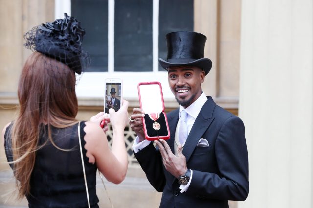 Sir Mo's wife Tania takes his photo outside Buckingham Palace (Jonathan Brady/PA)