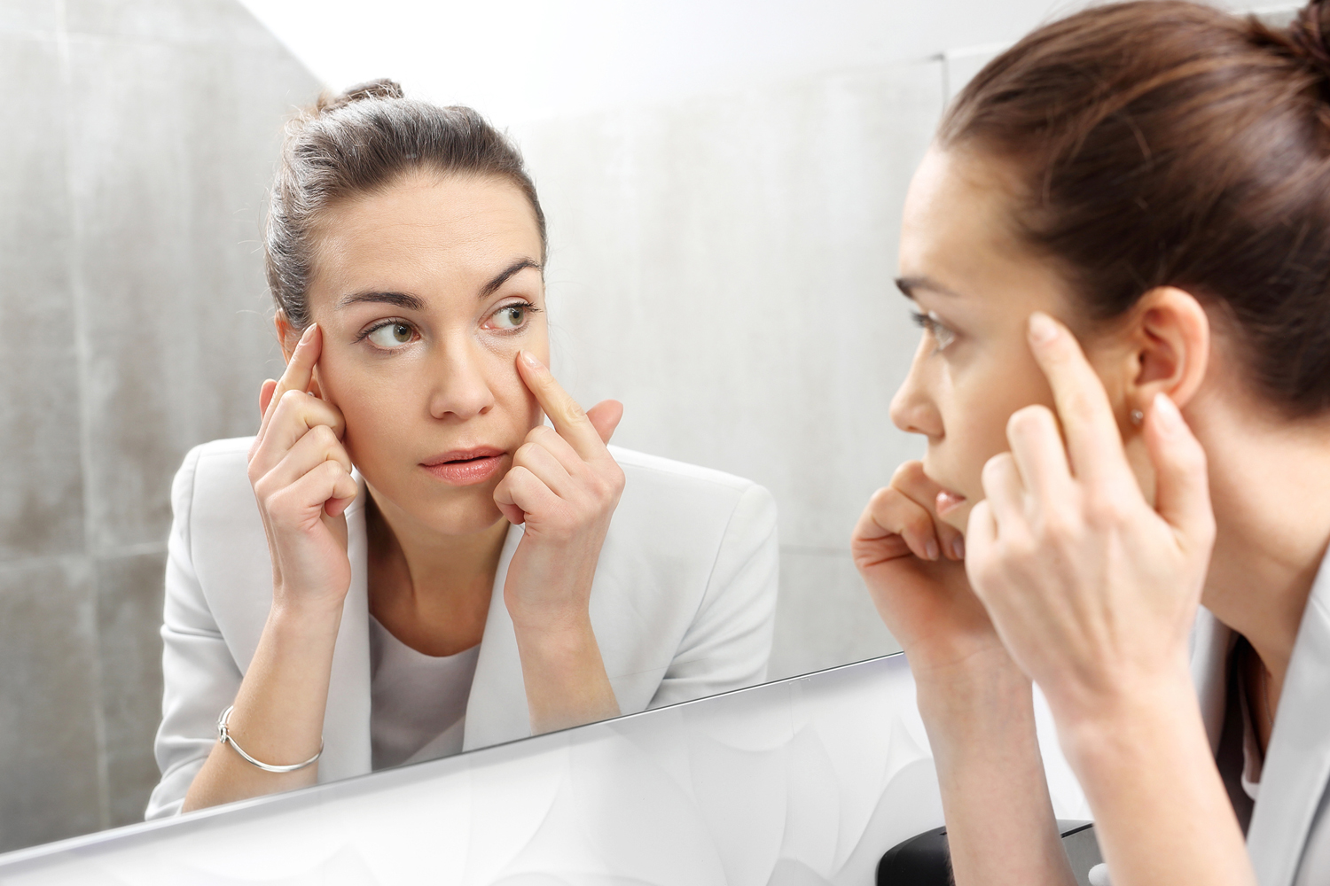 Woman looks in the mirror noticing the first wrinkles