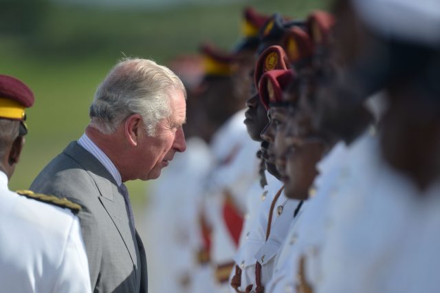 The Prince of Wales speaks to a member of the Antigua and Barbuda Defence Force and Royal Police as he arrives at VC Bird International Airport in Antigua