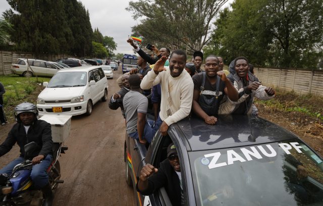 Protesters ride in a car with the name of the ruling party, calling for Mugabe to step down at a demonstration at Zimbabwe Grounds in Harare