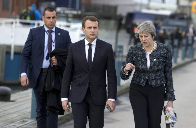 Theresa May speaks with French President Emmanuel Macron as they walk on a pier at an EU summit in Gothenborg