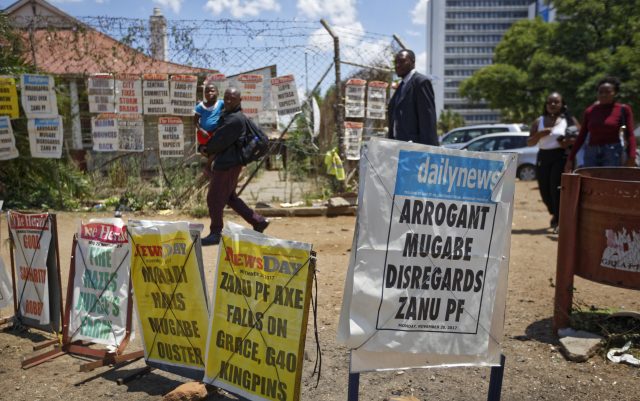 Pedestrians walk past a news stand in Harare