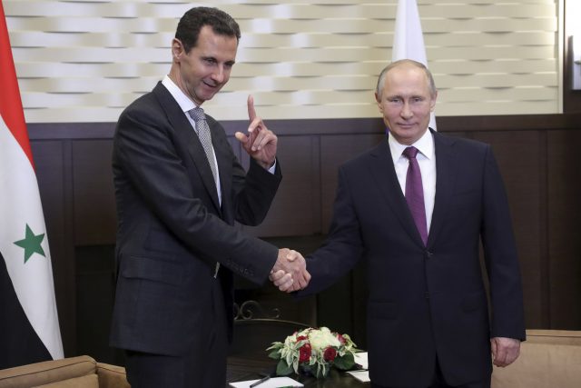 Russian President Vladimir Putin, right, shakes hands with Syrian President Bashar Assad