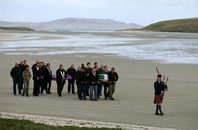 The coffin of Eilidh MacLeod draped in the Barra flag is carried across Traigh Mhor beach 