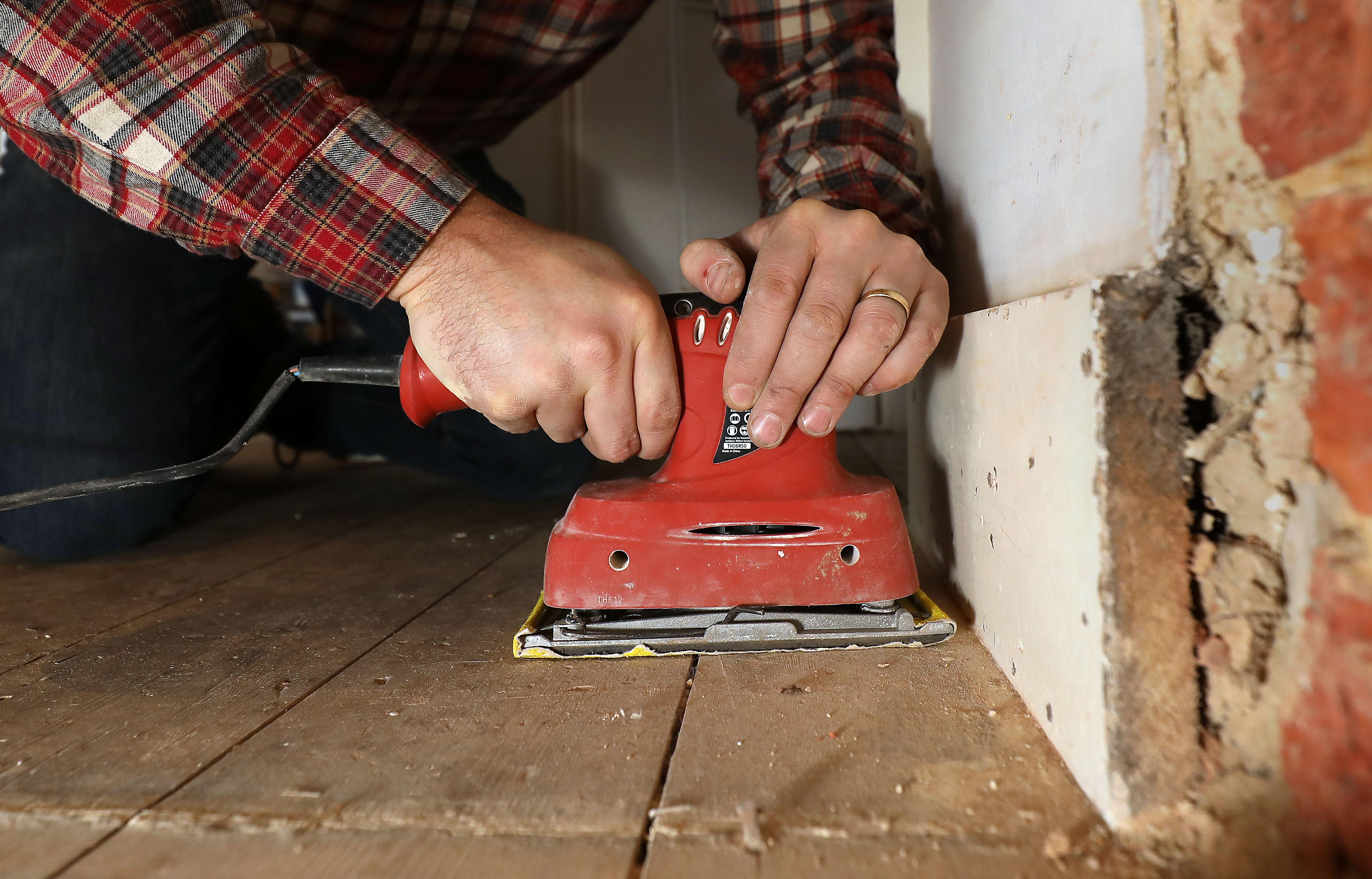 Richard Burr sands the corners of a floor