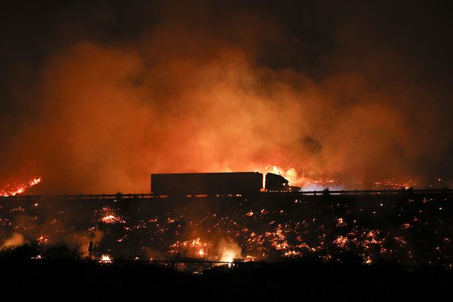 A truck drives along the 101 Freeway in Ventura through flames (AP)