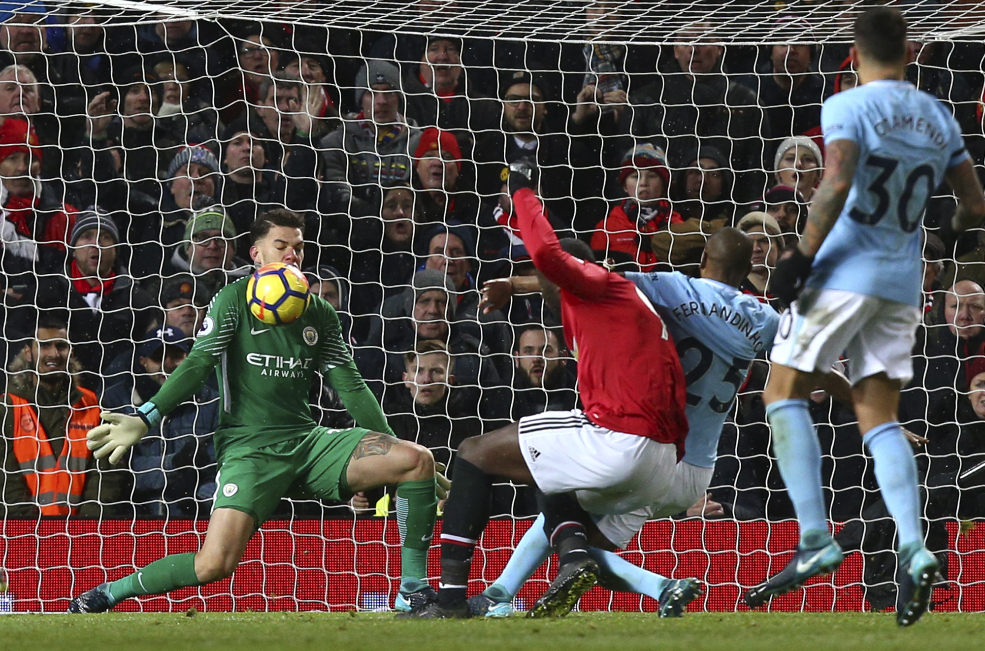 Manchester City goalkeeper Ederson, left, stops a shot from Manchester United's Romelu Lukaku