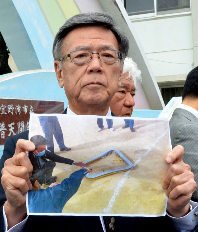 Okinawa governor  Takeshi Onaga holds a picture of a metal window frame that fell from the aircraft (Kazuki Sawada/Kyodo News via AP)