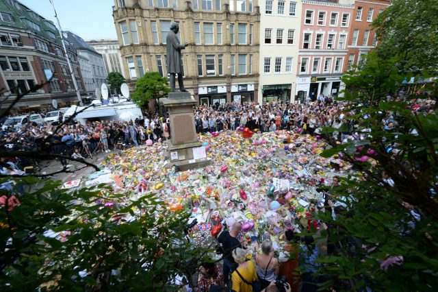 Crowds look at the floral tributes after a minute's silence in St Ann's Square, Manchester, to remember the victims of the terror attack at the Manchester Arena during an Ariana Grande gig (Ben Birchall/PA)