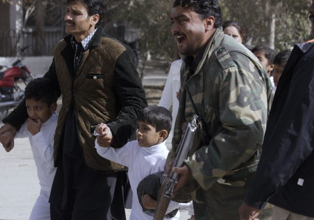 A police officer shouts as children are rescued from the building (Arshad Butt/PA)
