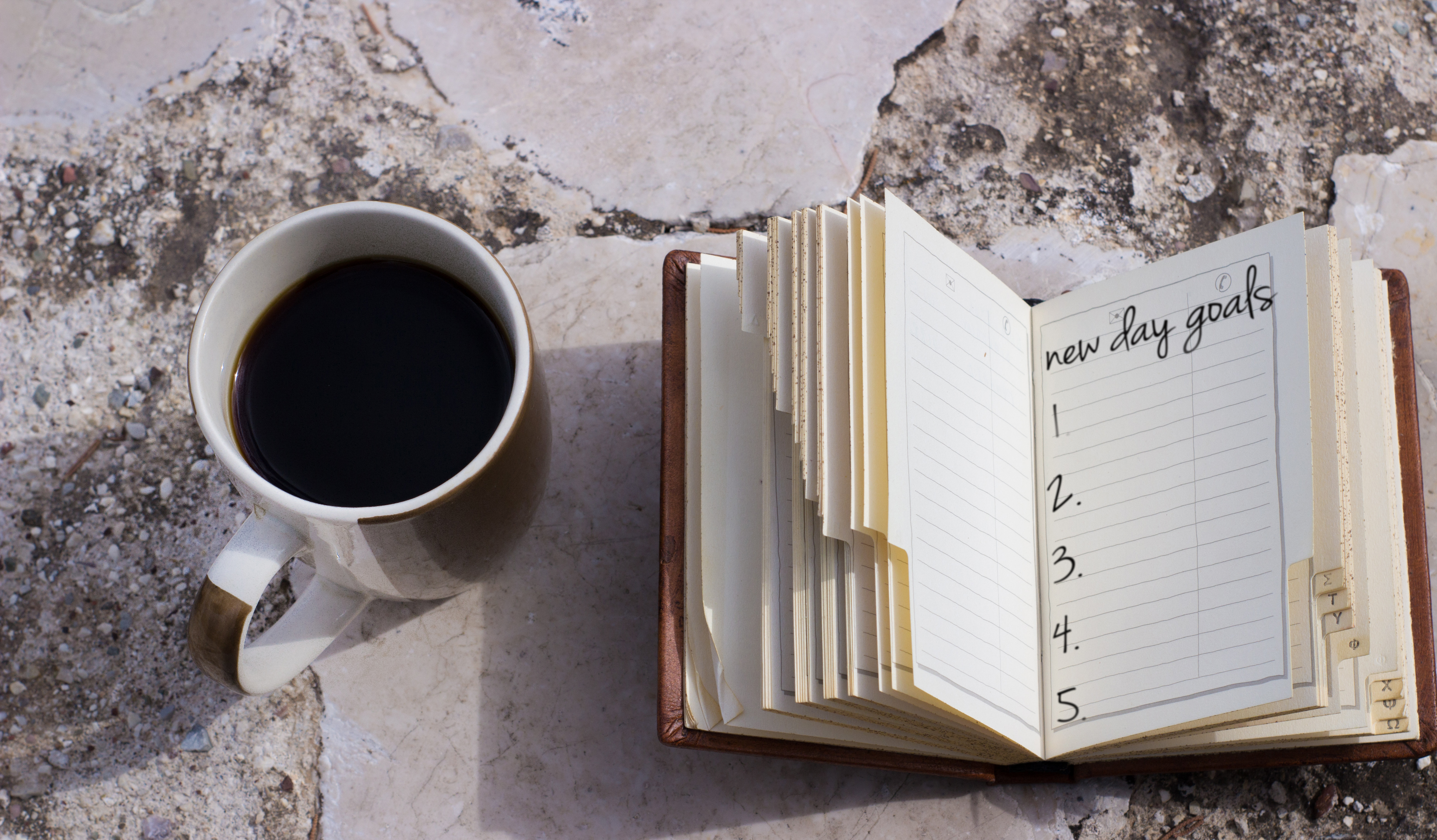 coffee mug and a small notebook with a list of goals with copy space numbered list