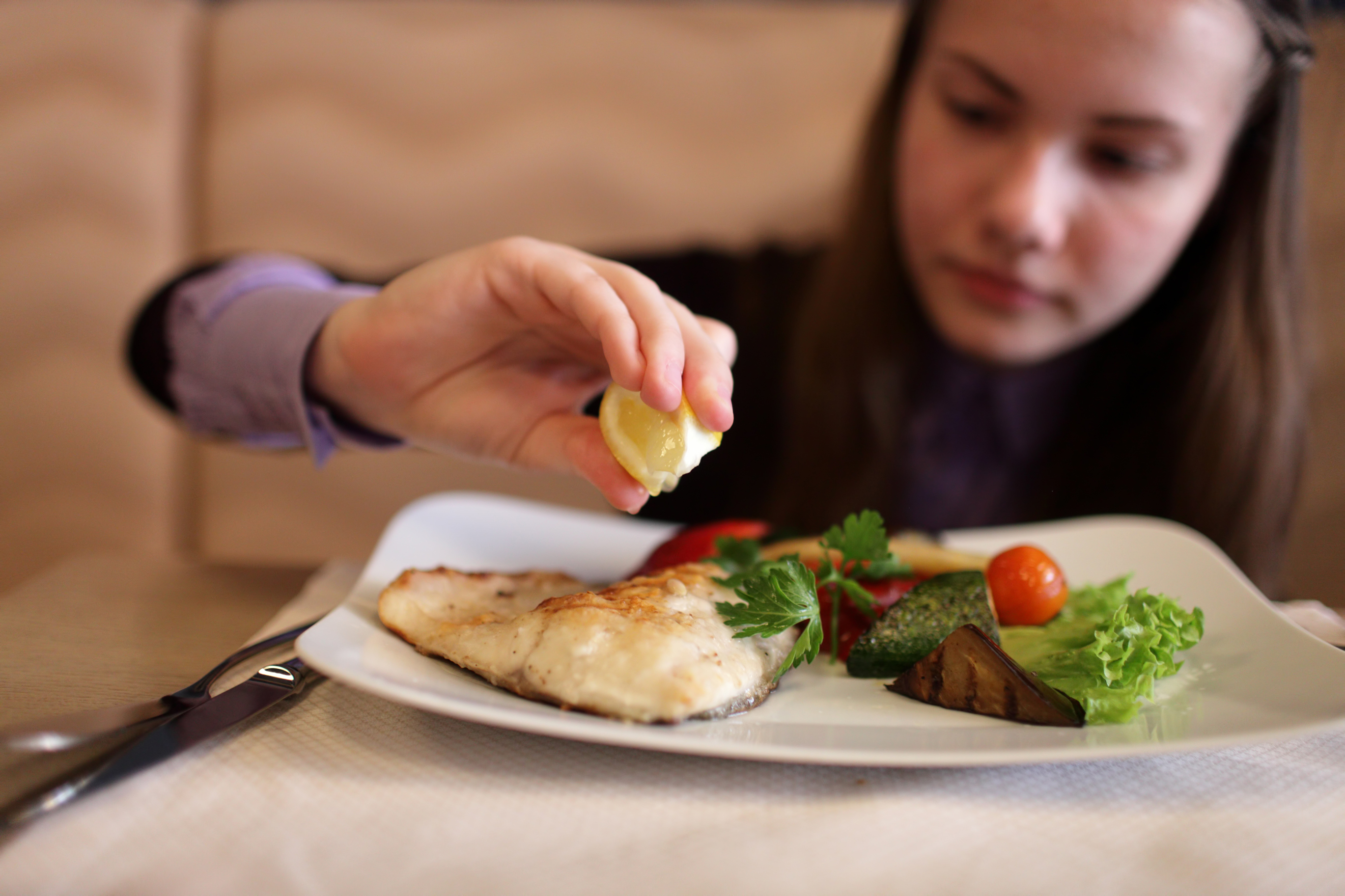 A teenager eating fish.