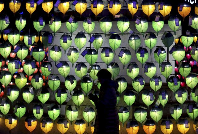 A woman prays in front of lanterns to celebrate the new year at a Buddhist temple in Seoul, South Korea (Ahn Young-joon/AP)