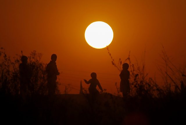 Children from a slum area play as the sun sets for the last time in 2017, on the outskirts of Islamabad, Pakistan (Anjum Naveed/AP)