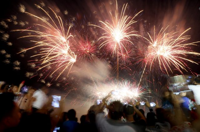 Revellers watch as fireworks light up the sky at the seaside Mall of Asia south of Manila, Philippines (Bullit Marquez/AP)