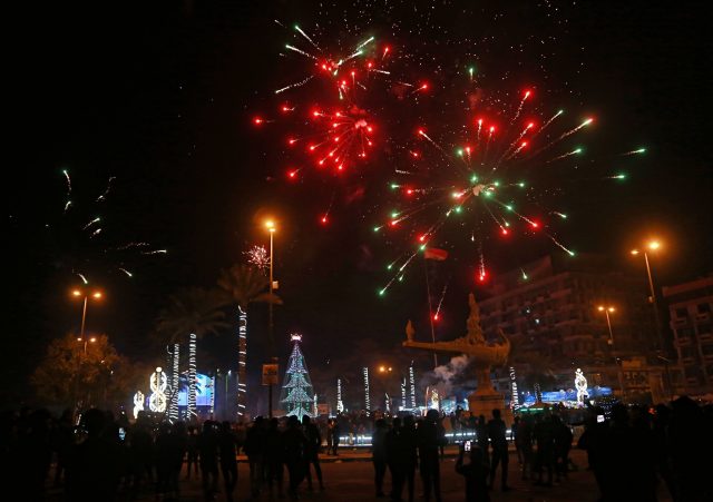 Iraqis watch fireworks explode during the new year celebrations in Baghdad (Khalid Mohammed/AP)