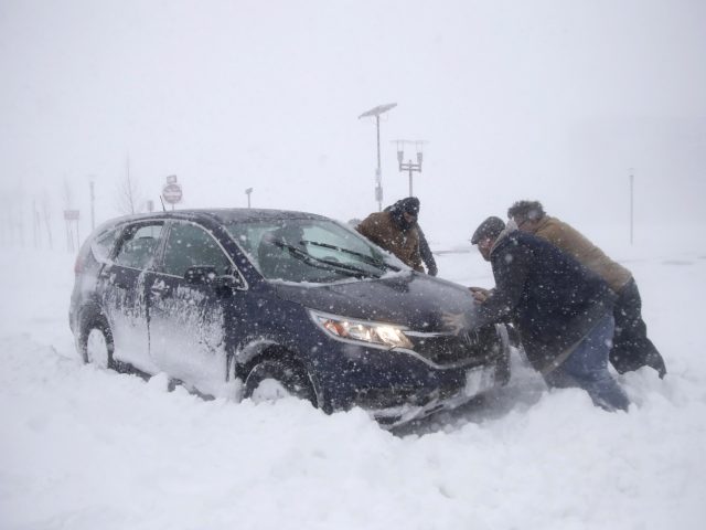 A group of men help a motorist after his vehicle was stuck in the snow near Asbury Park in New Jersey (Julio Cortez/AP/PA)