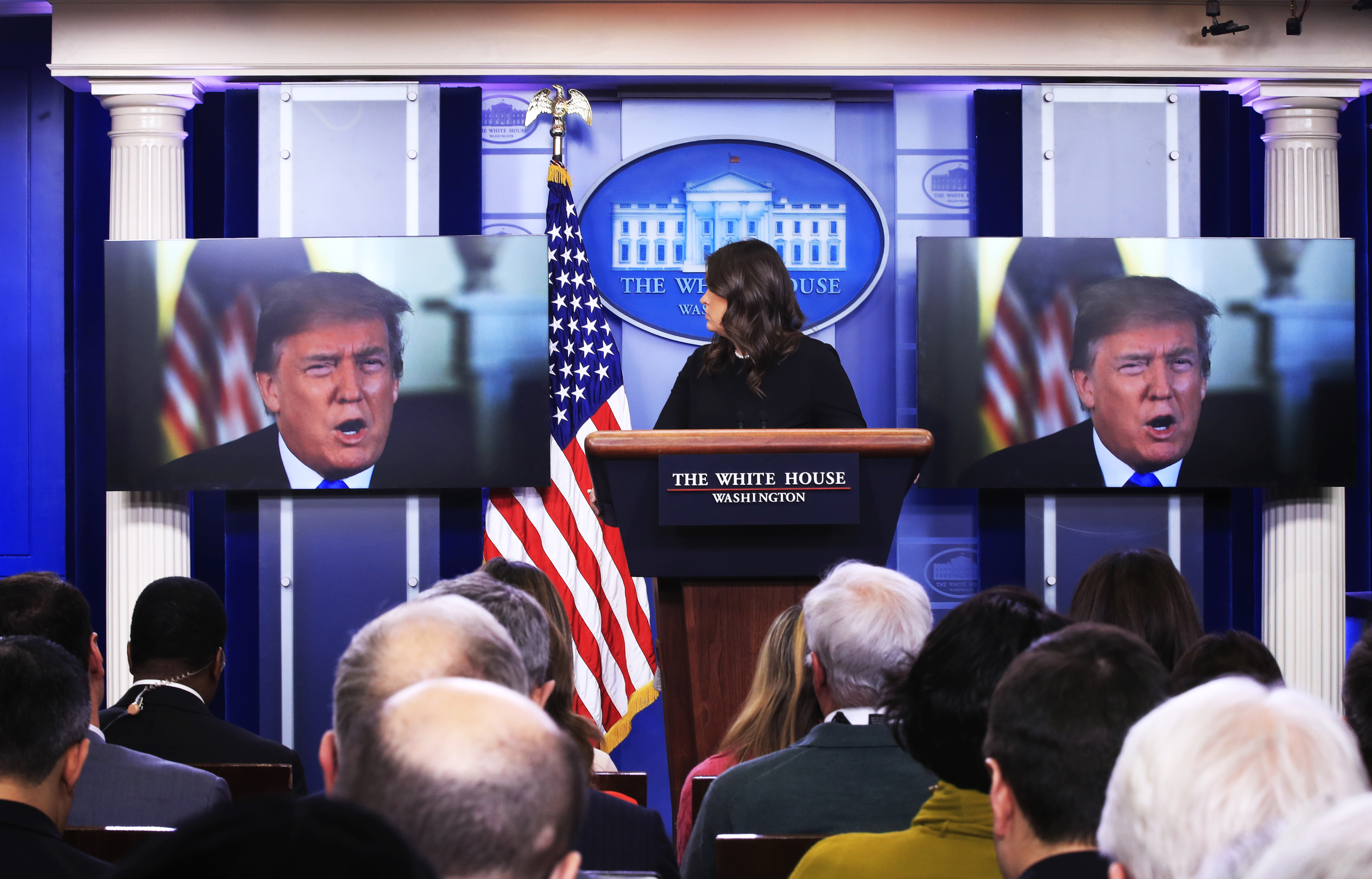 Trump appears on video behind Sarah Huckabee Sanders