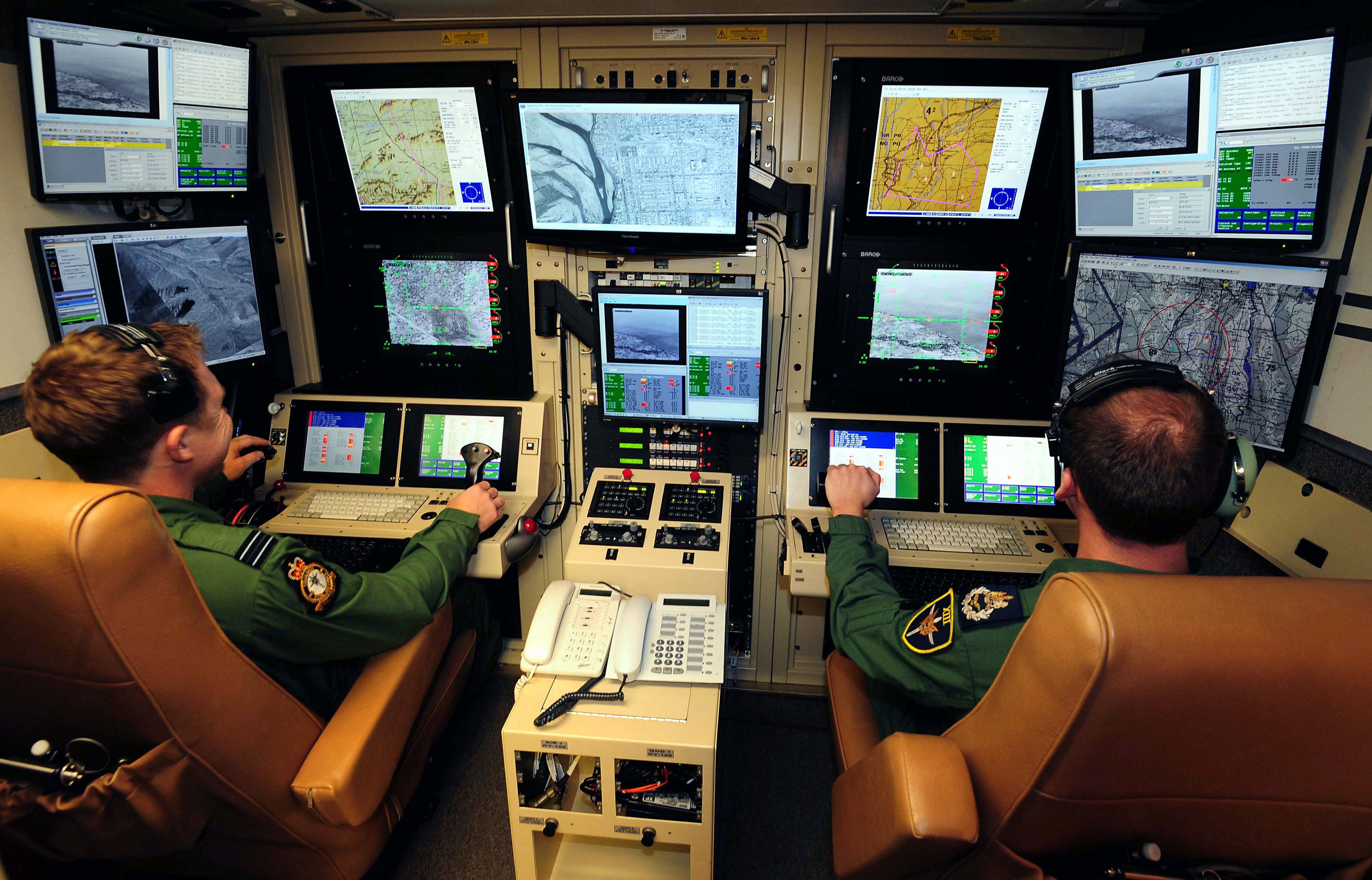 Operators sitting in the ground control operating station for a remotely piloted air system in the RAF