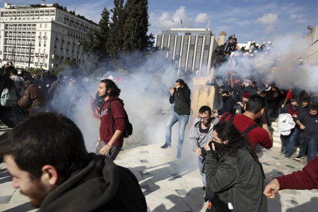 Protesters try to avoid tear gas fired by police (Thanassis Stavrakis/AP)