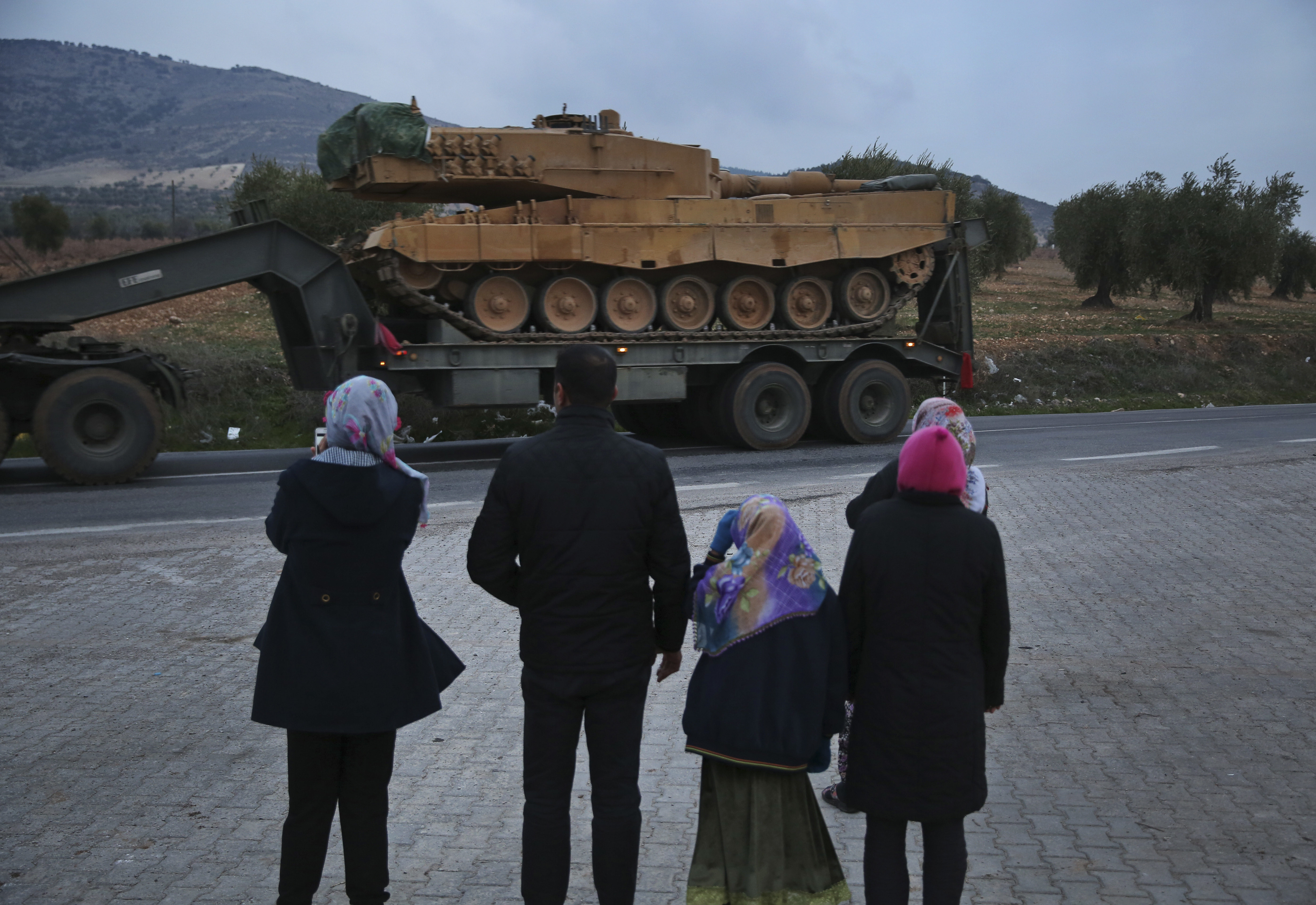 Residents watch as a truck, part of a convoy, transporting a Turkish army tank is driven in the outskirts of the town of Kilis, Turkey, near the border with Syria (Lefteris Pitarakis/AP)