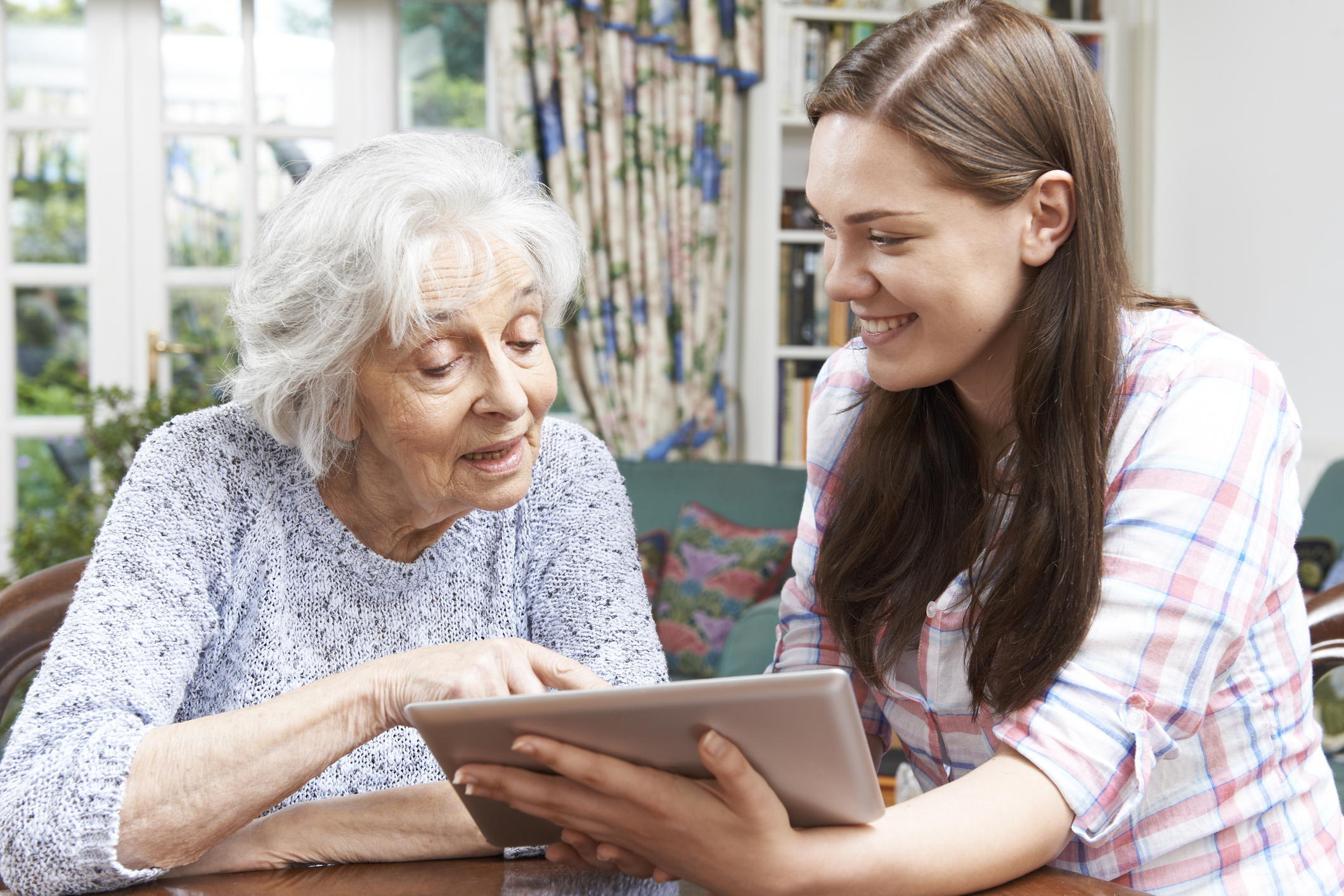 Teenage Granddaughter Showing Grandmother How To Use Digital Tablet