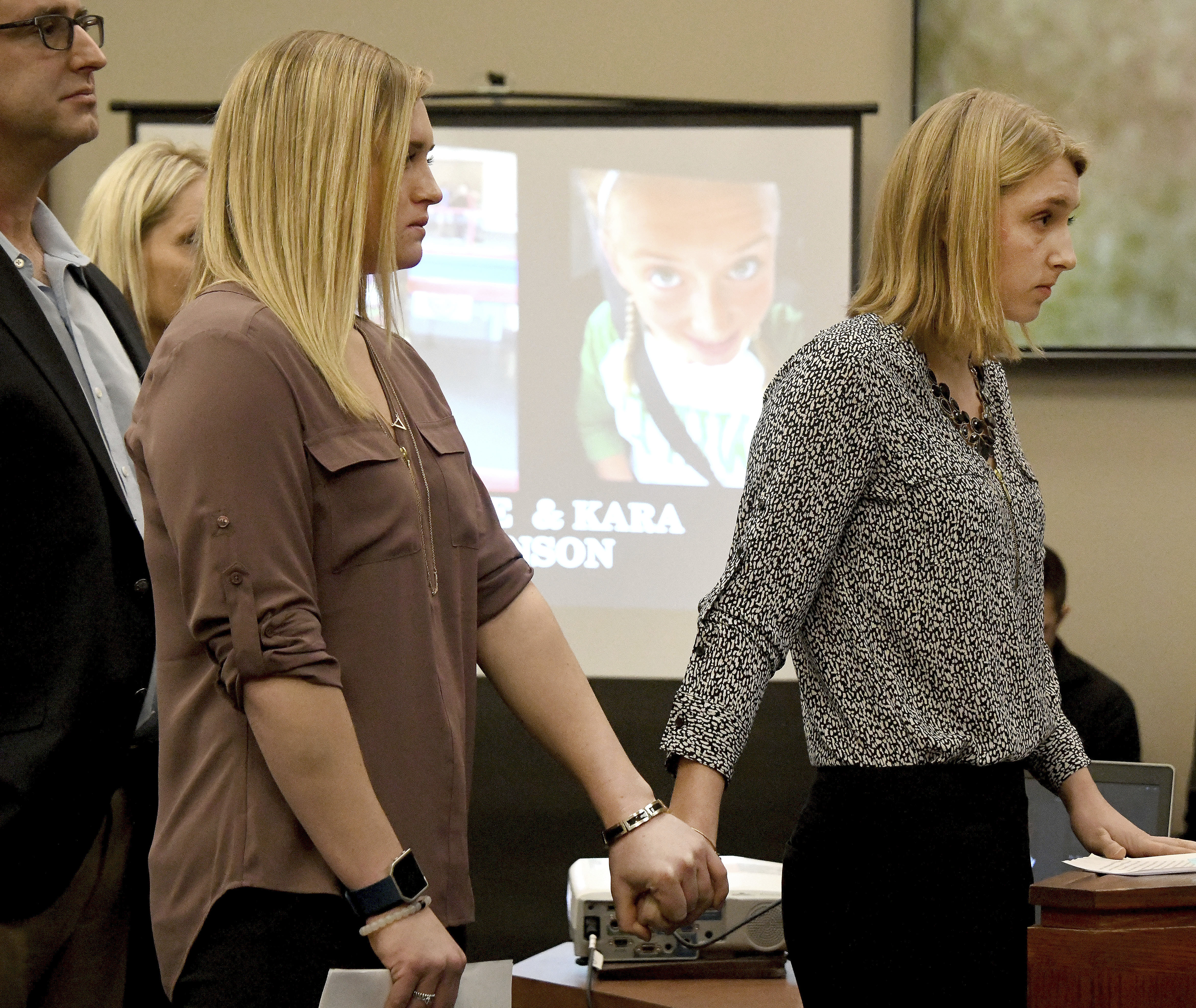 Sisters Maddie, left, and Kara Johnson hold hands as they make their victim impact statements (Dale G Young/Detroit News via AP)