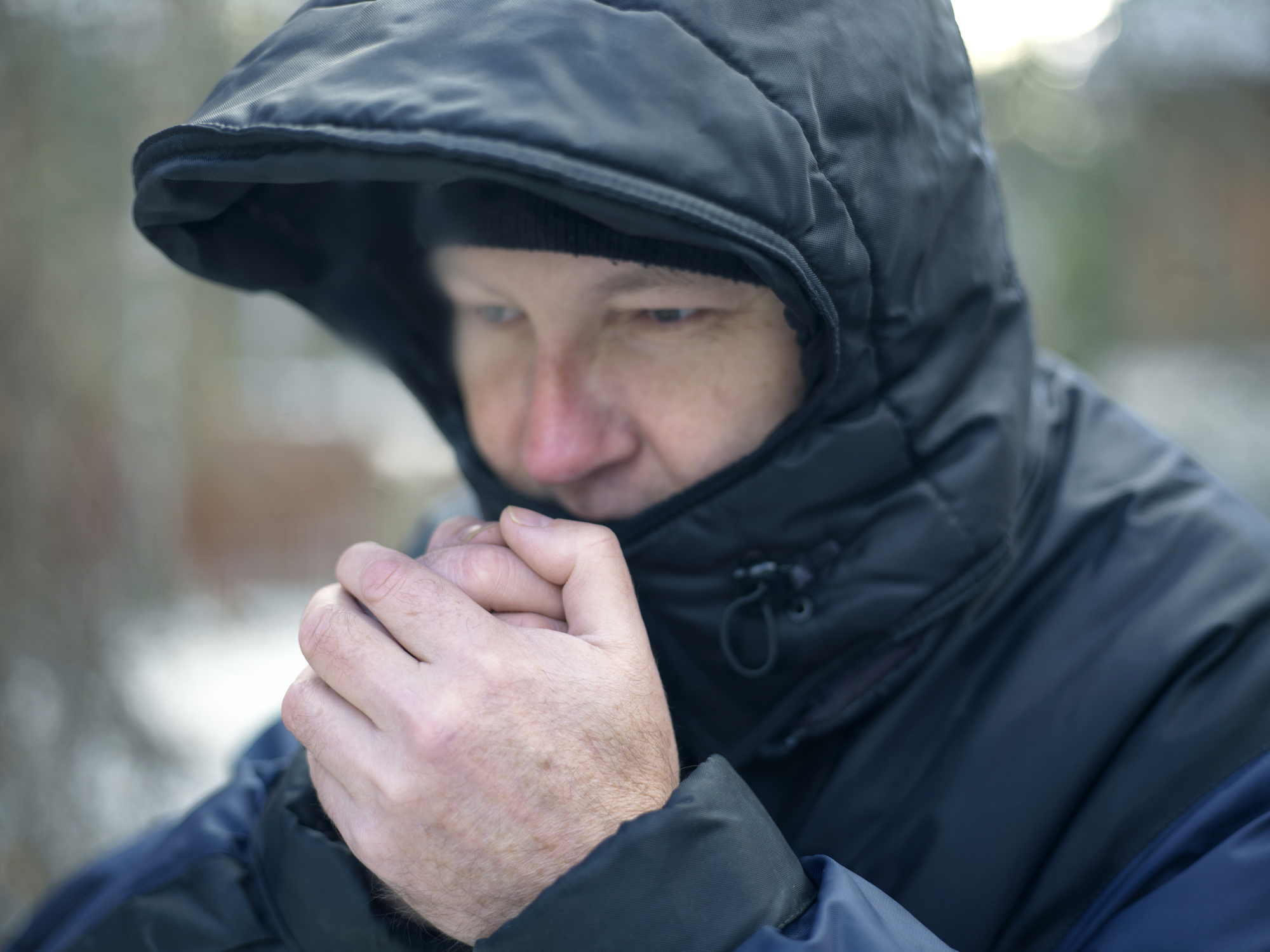 Man wearing hood warming his hands