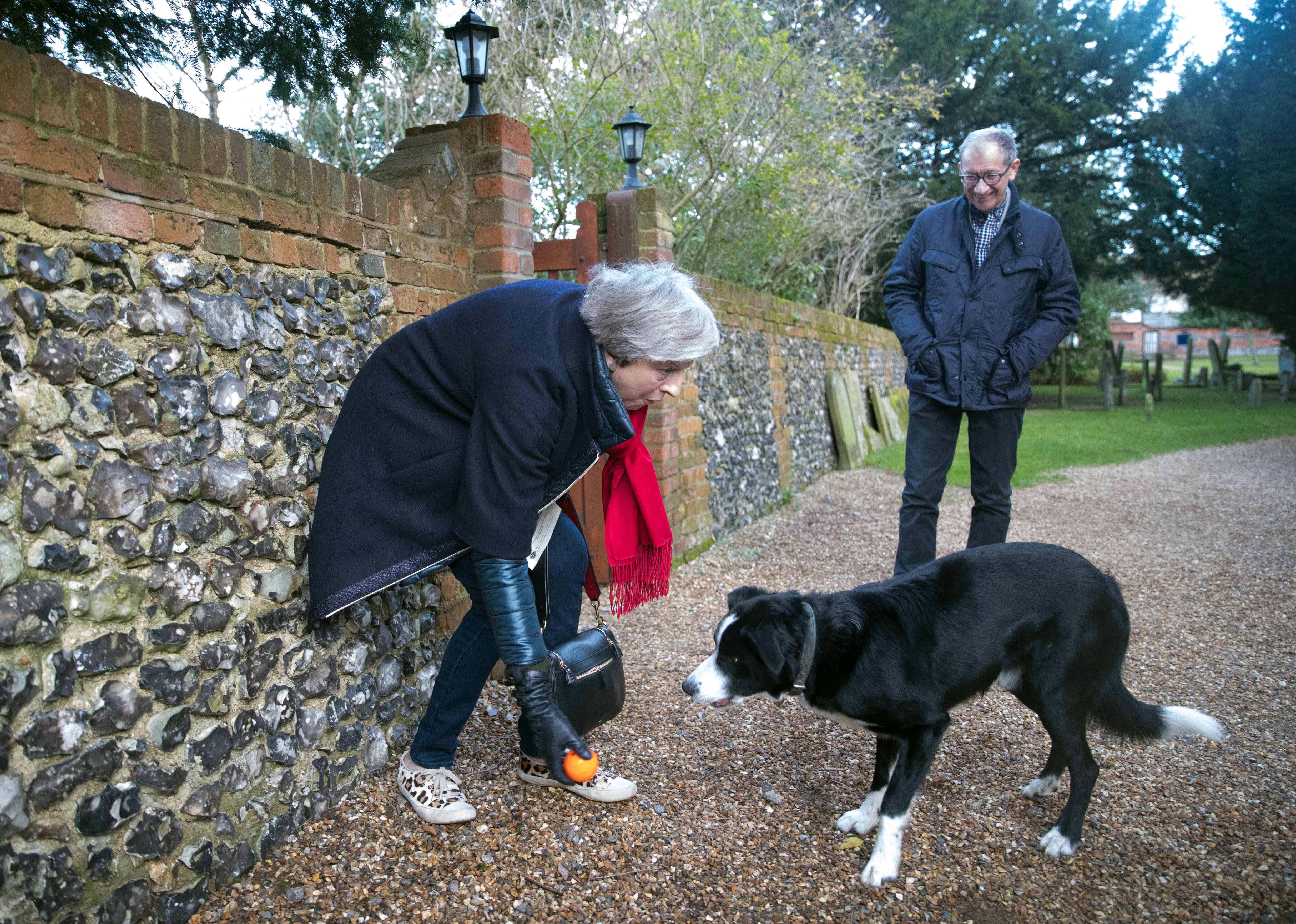 Prime Minister Theresa May, watched by her husband Philip, throws a ball for a Border Collie called Blitz as they leave after attending church (Steve Parsons/PA)