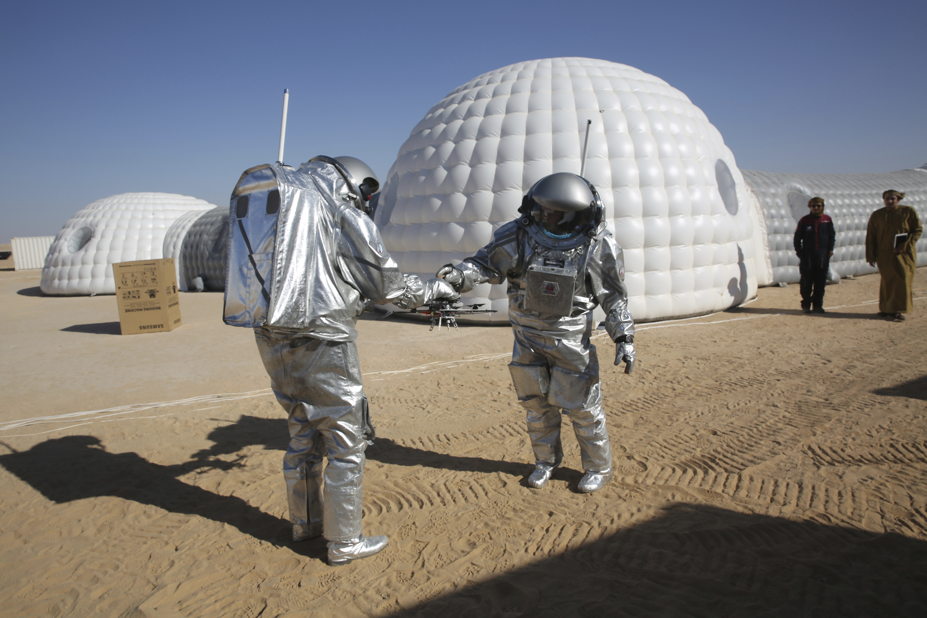 Analogue astronaut Joao Lousada hands his colleague Kartik Kumar a drone (Sam McNeil/AP)