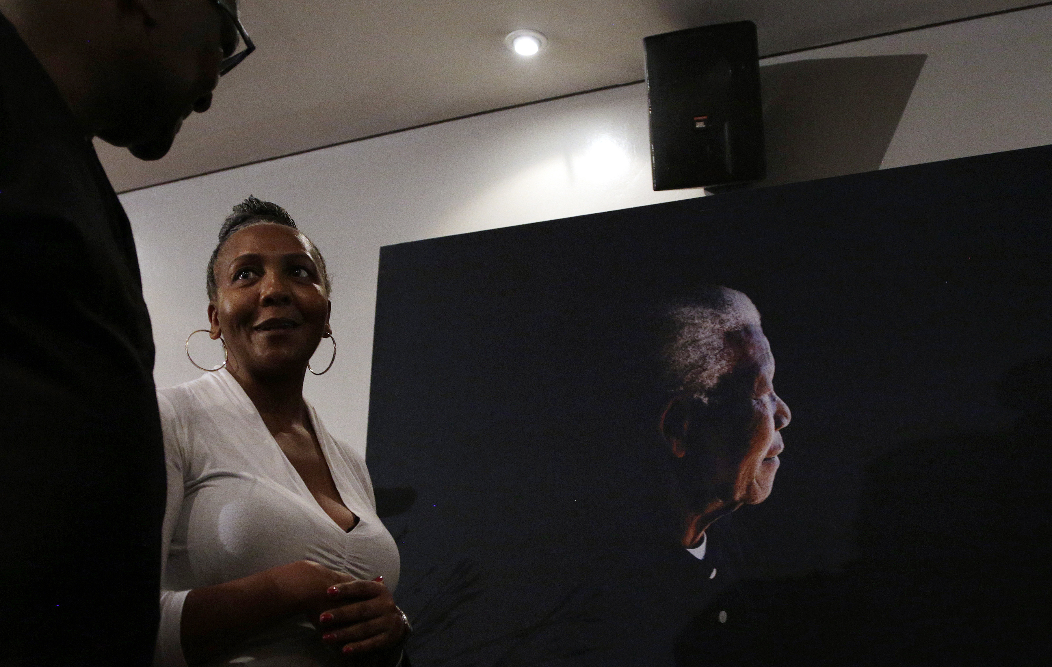 Ndileka Mandela, the granddaughter of former president Nelson Mandela, walks past a poster of her grandfather during the unveiling of the Mandela rose (Themba Hadebe/AP)